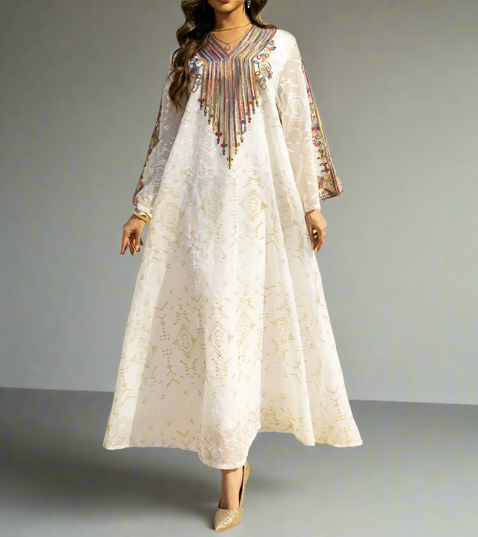 Woman wearing a long, light-colored dress with intricate patterns in a desert setting